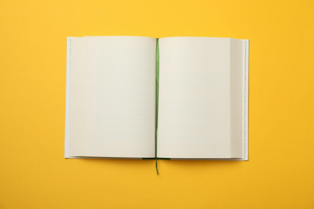 Opened empty book on yellow background, space for text