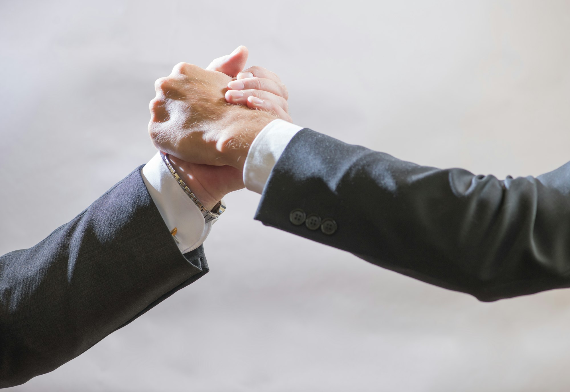 Two business partner to greet each other, branded handshake on gray background