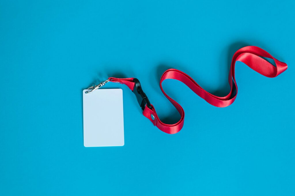 White plastic badge, red Lanyard with blank space mock up isolated on blue background