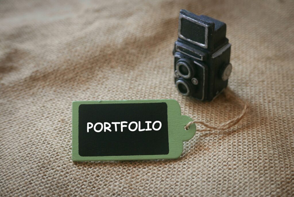 A miniature of a black vintage camera together with a wooden tag written with Portfolio.